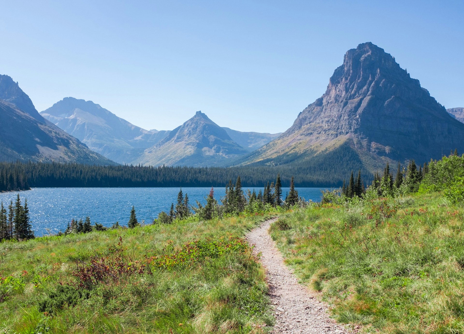 Hiking trail leading toward a lake and mountain peaks in Montana